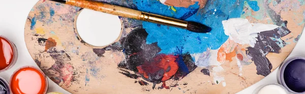 Top view of palette with Gouache paints and paintbrush on white background, panoramic shot — Stock Photo