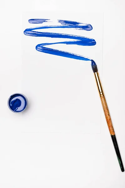 Vue de dessus du coup de pinceau bleu et du pinceau sur fond blanc — Photo de stock