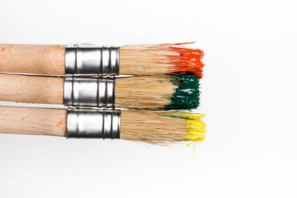 Vue de dessus des pinceaux avec peinture colorée sur fond blanc — Photo de stock