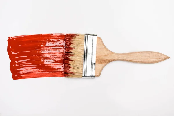 Top view of paintbrush near colorful red paint brushstroke on white background — Stock Photo