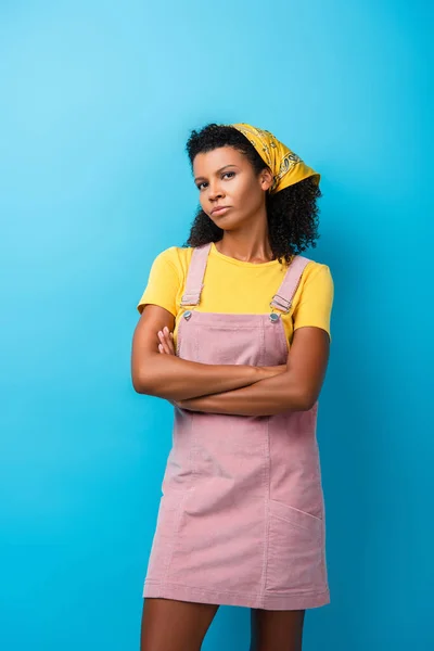 Cético Africano americano mulher de pé com braços cruzados em azul — Fotografia de Stock