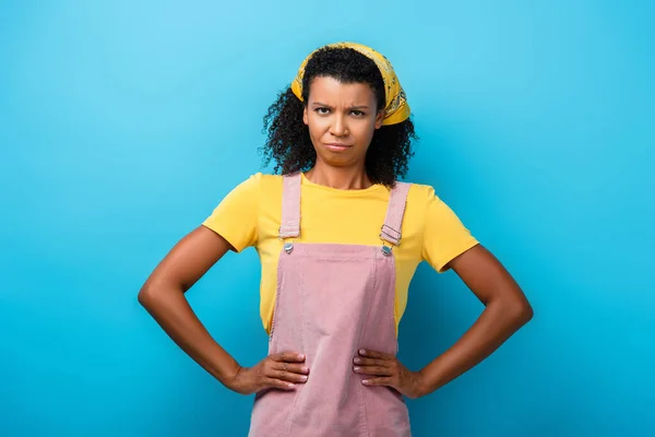 Displeased african american woman standing with hands on hips on blue — Stock Photo