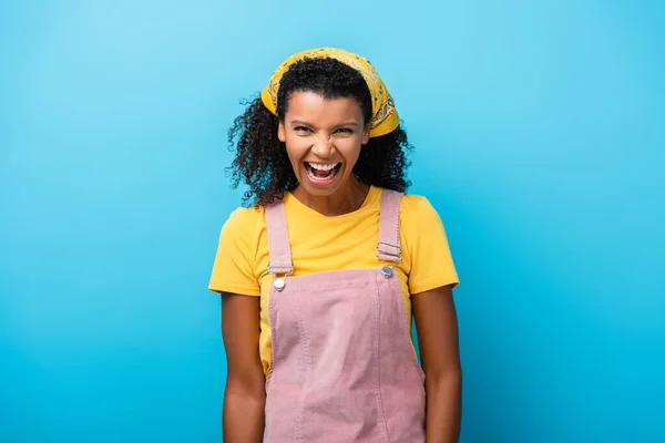 Mujer afroamericana con la boca abierta riendo en azul - foto de stock