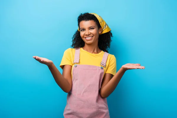 Happy african american woman pointing with hands on blue — Stock Photo