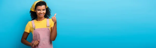 Fröhliche afrikanisch-amerikanische Frau zeigt Daumen hoch auf blau, Banner — Stockfoto