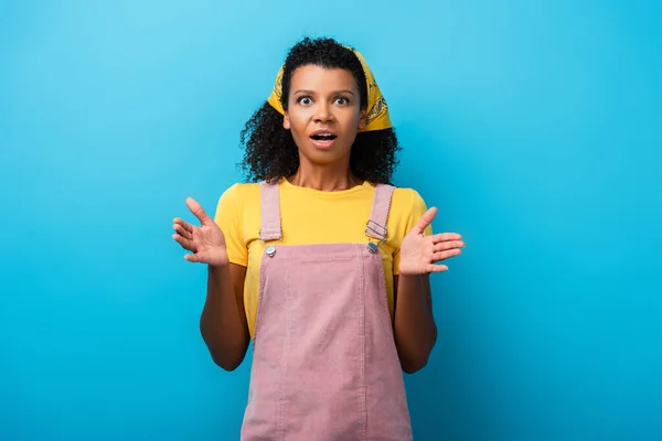 Chocado afro-americano mulher gesticulando no azul — Fotografia de Stock