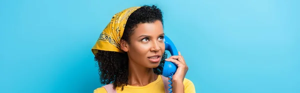 Curly african american woman talking on retro telephone on blue, banner — Stock Photo