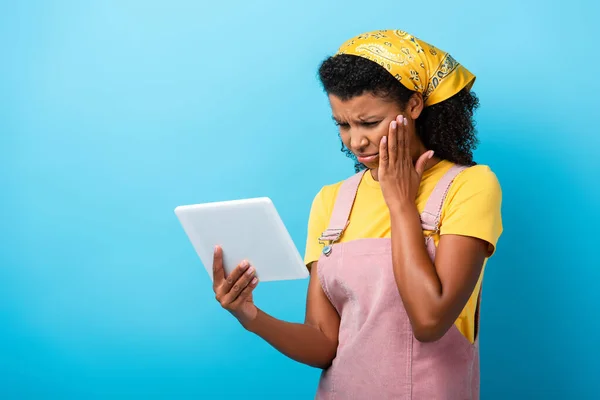 Sconvolto donna afroamericana in velo utilizzando tablet digitale su blu — Foto stock