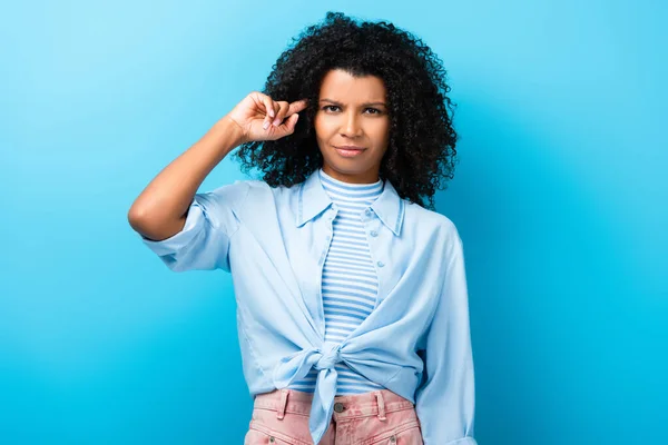 Mujer afroamericana disgustado señalando con el dedo en la cabeza en azul - foto de stock