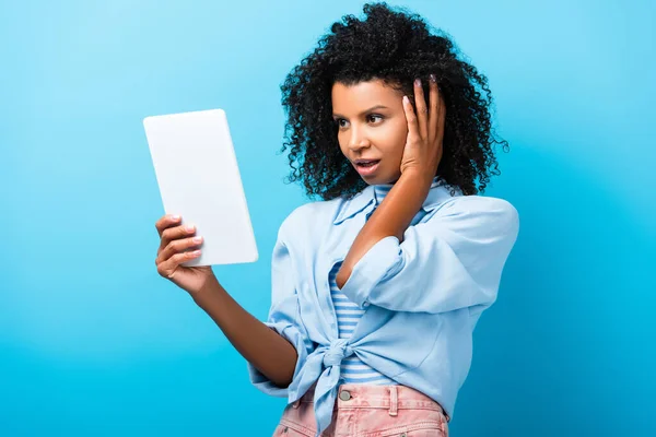 Удивленный африканский американец женщина, использующая цифровой планшет на синий — стоковое фото
