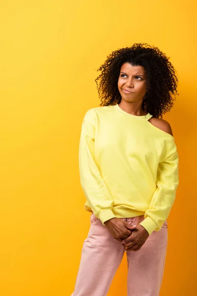 Mujer afroamericana disgustada mirando hacia otro lado en amarillo - foto de stock