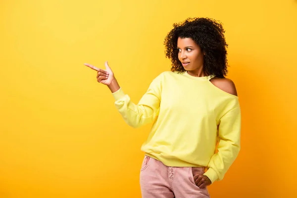 Surprised african american woman pointing with finger on yellow — Stock Photo