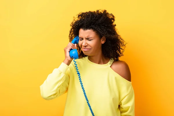 Bouleversé afro-américain femme parler sur vintage téléphone sur jaune — Photo de stock