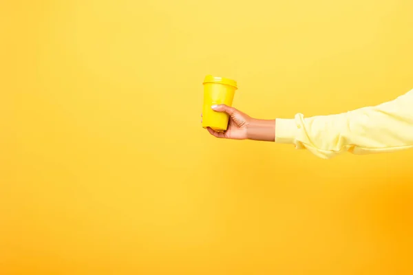 Vista parziale della donna afro-americana in possesso di tazza riutilizzabile su giallo — Foto stock