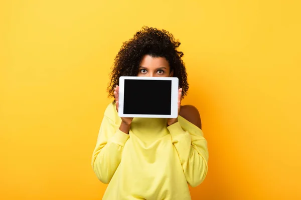Afroamerikanerin bedeckt Gesicht mit digitalem Tablet mit leerem Bildschirm auf gelb — Stockfoto
