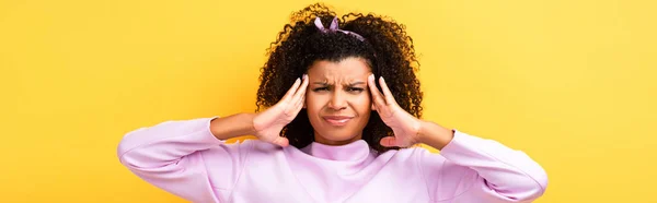 Femme afro-américaine mécontente ayant la migraine sur jaune, bannière — Photo de stock
