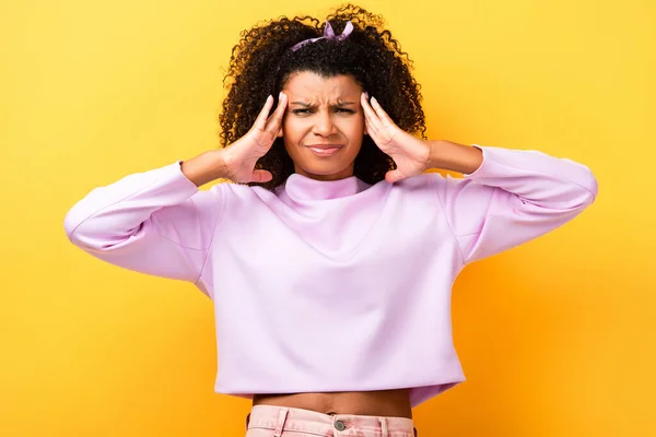 Displeased african american woman having migraine on yellow — Stock Photo