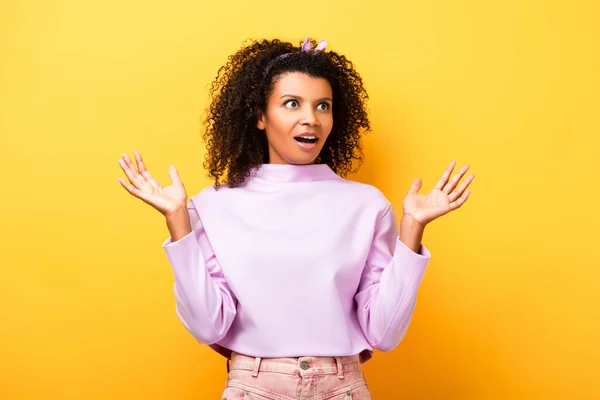 Étonné heureux afro-américain femme geste sur jaune — Photo de stock