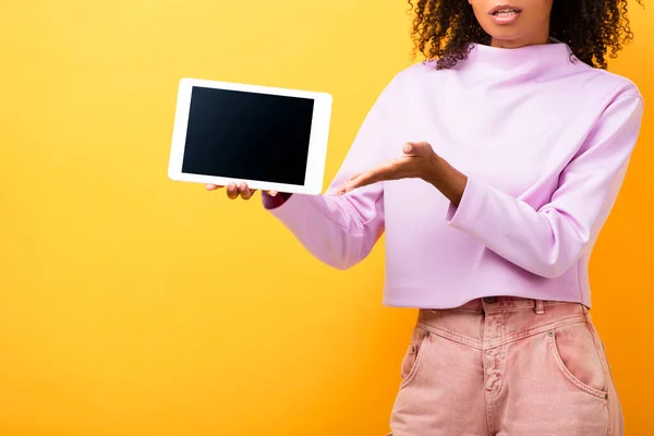 Vue partielle de la femme afro-américaine pointant avec la main tablette numérique avec écran blanc sur jaune — Photo de stock