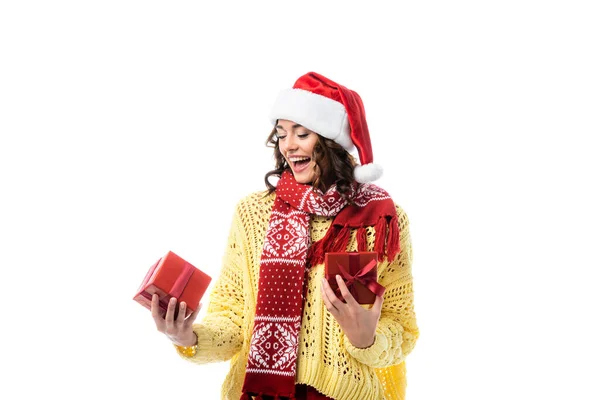 Mujer excitada en sombrero de santa y bufanda roja mirando al presente aislado en blanco - foto de stock