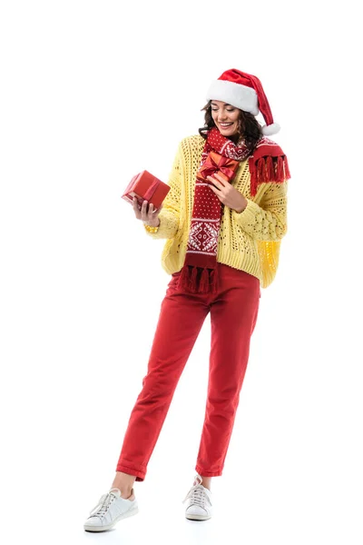 Pleased woman in santa hat and red scarf holding presents isolated on white — Stock Photo