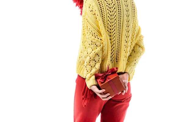 Cropped view of young woman in knitted sweater holding present behind back isolated on white — Stock Photo