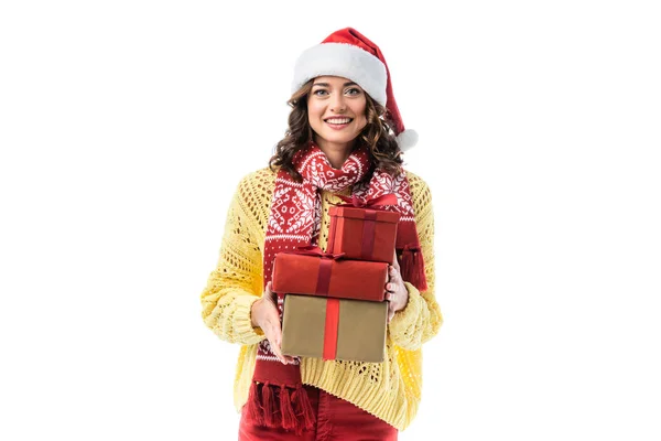 Радісна молода жінка в капелюсі Санта і шарфі, що тримає подарунки ізольовані на білому — стокове фото