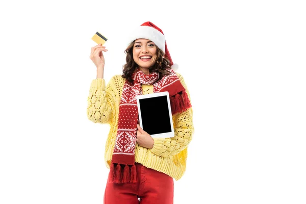 Joyful woman in santa hat and scarf holding digital tablet with blank screen and credit card isolated on white — Stock Photo