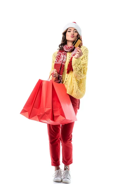 Woman with duck face, in santa hat and scarf with ornament holding shopping bags and credit card isolated on white — Stock Photo