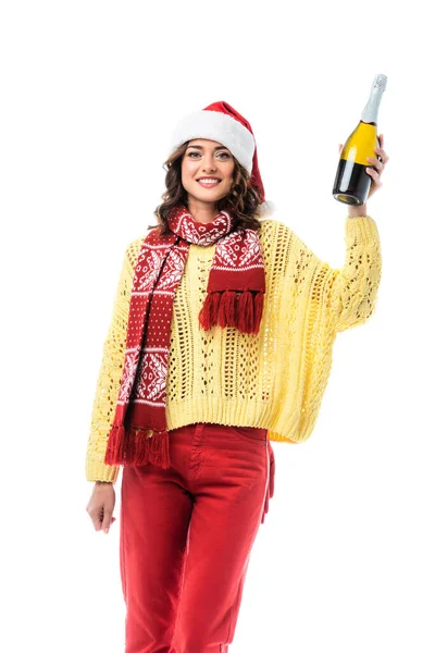 Joyeuse jeune femme en santa chapeau et écharpe avec ornement tenant bouteille de champagne isolé sur blanc — Photo de stock