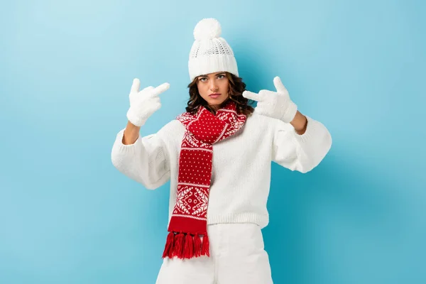 Scontento giovane donna in abito bianco inverno mostrando dita medie su blu — Foto stock