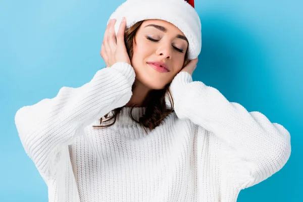 Jeune femme brune avec les yeux fermés touchant chapeau sur bleu — Photo de stock