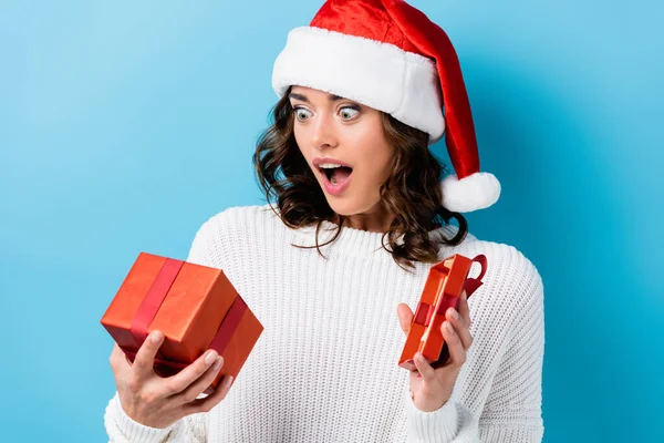 Young shocked woman looking at gift box on blue — Stock Photo