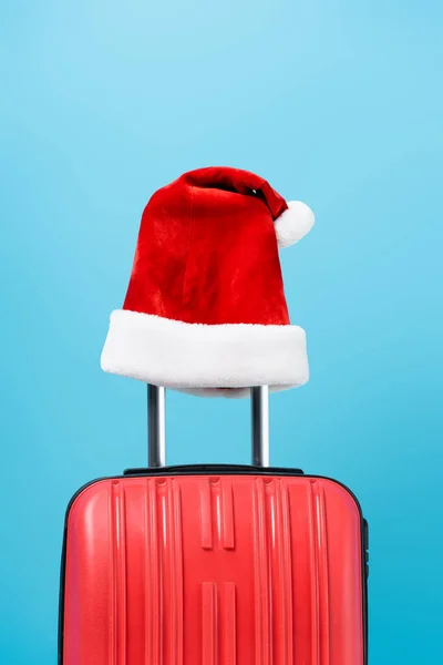 Chapeau santa rouge sur sac de voyage moderne isolé sur bleu — Photo de stock