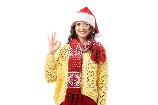 Jovem mulher alegre em santa chapéu e cachecol vermelho mostrando ok sinal isolado no branco — Fotografia de Stock