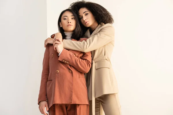 African american and asian women in formal wear posing on white — Stock Photo