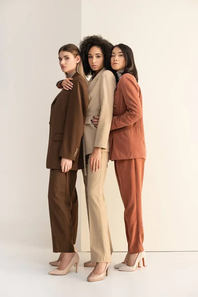 Full length of young multicultural women in formal wear posing on white — Stock Photo