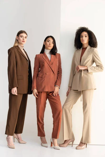 Full length of interracial women in formal wear posing on white — Stock Photo