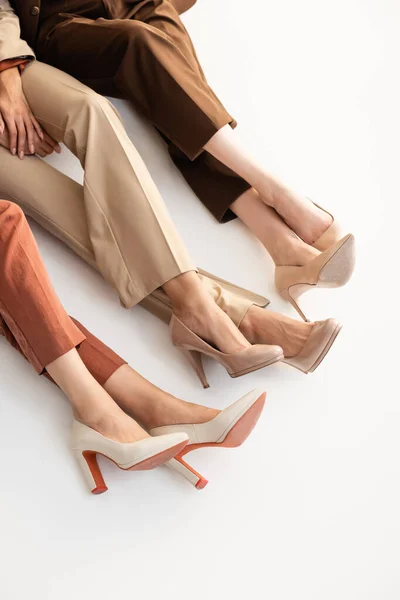 Высокий угол обзора женщин в модных брюках и туфлях на высоком каблуке на белом — стоковое фото