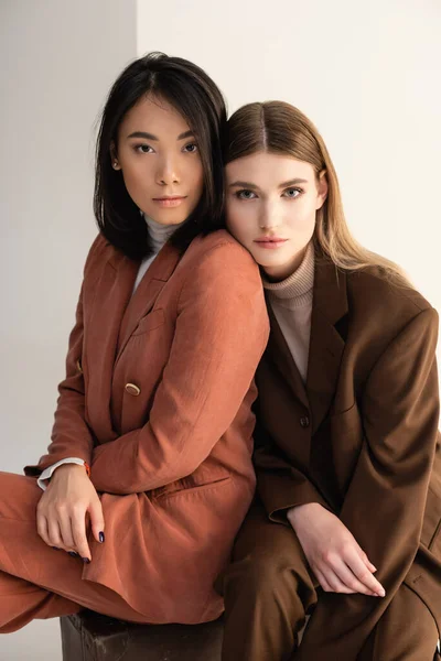 Young interracial women in trendy pastel suits looking at camera on white — Stock Photo