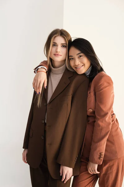 Joven elegante modelo posando con feliz asiático mujer en blanco - foto de stock