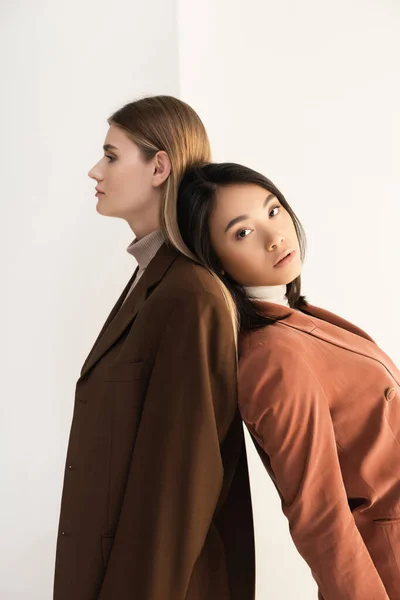 Young stylish model posing with brunette asian woman on white — Stock Photo