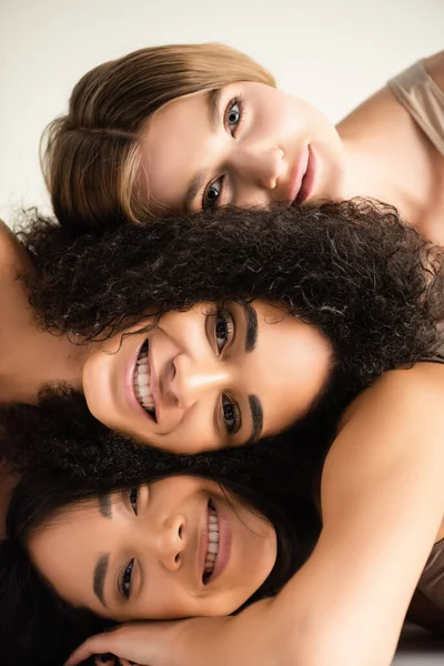 Vista superior de jóvenes modelos multiculturales positivos mirando a la cámara aislada en blanco - foto de stock