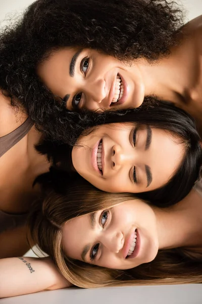 Vista superior de modelos multiculturais felizes olhando para a câmera isolada no branco — Fotografia de Stock