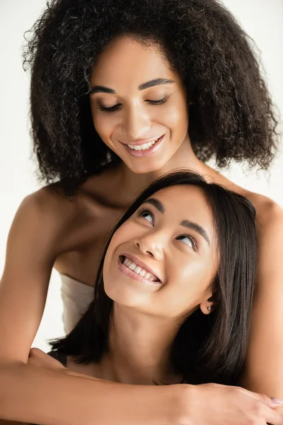 Feliz Africano americano e asiático mulheres olhando para o outro isolado no branco — Fotografia de Stock