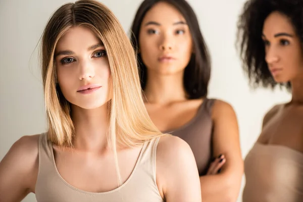 Rubia mujer cerca africano americano y asiático modelos en borrosa fondo aislado en blanco - foto de stock