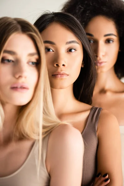 African american and asian women near blonde model on blurred foreground — Stock Photo