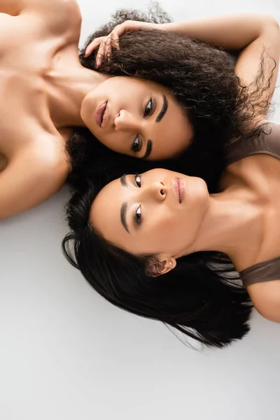 Вид зверху афроамериканських і азіатських жінок, що лежать ізольовані на білому — стокове фото