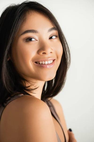 Morena mujer asiática sonriendo mientras mira a la cámara aislada en blanco - foto de stock