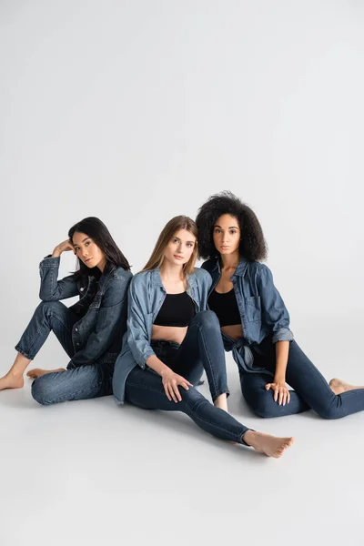 Junge interrassische Frauen im Jeans-Outfit posieren auf weiß — Stockfoto